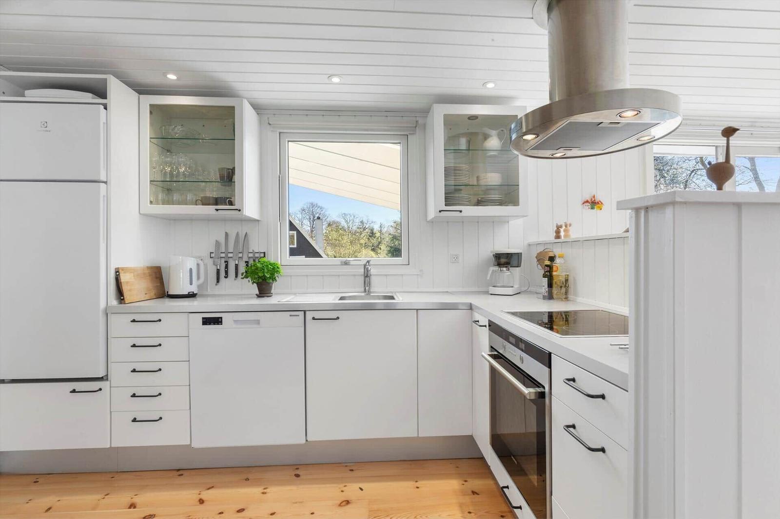Kitchen with white cabinets, stainless steel sink, and window with view outside.