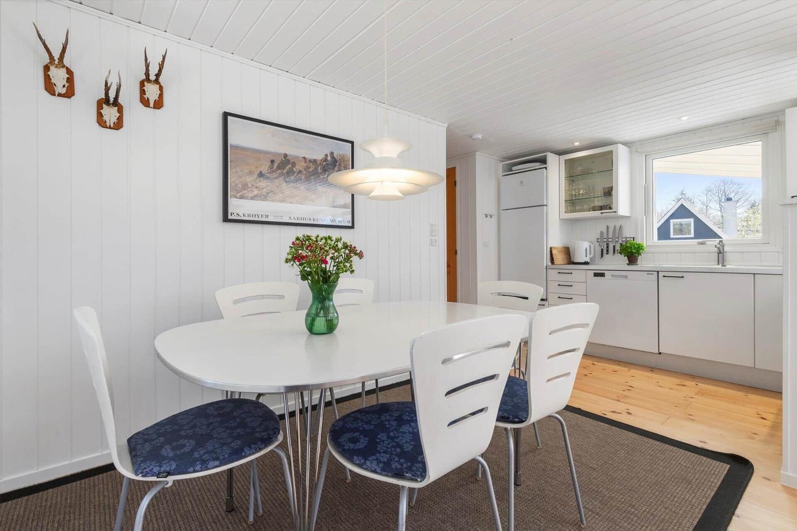 Dining area with white table and chairs, kitchenette and wall decor