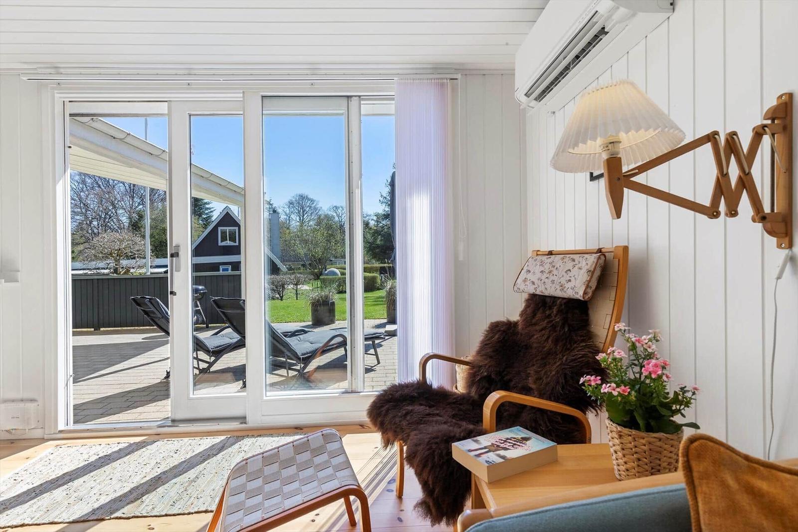 Room with chair, table, and view of terrace with loungers.