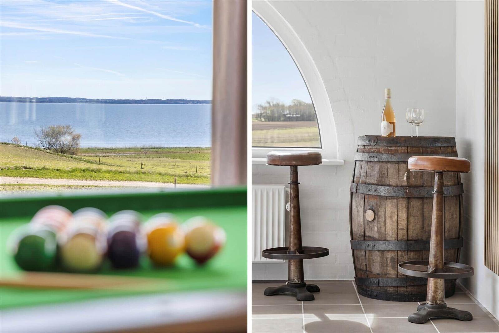 View of lake and green meadows. Wooden barrel with wine and two stools.