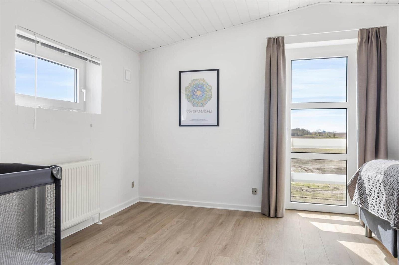 Bedroom with window, bed, and crib. Wooden floor and wall art.