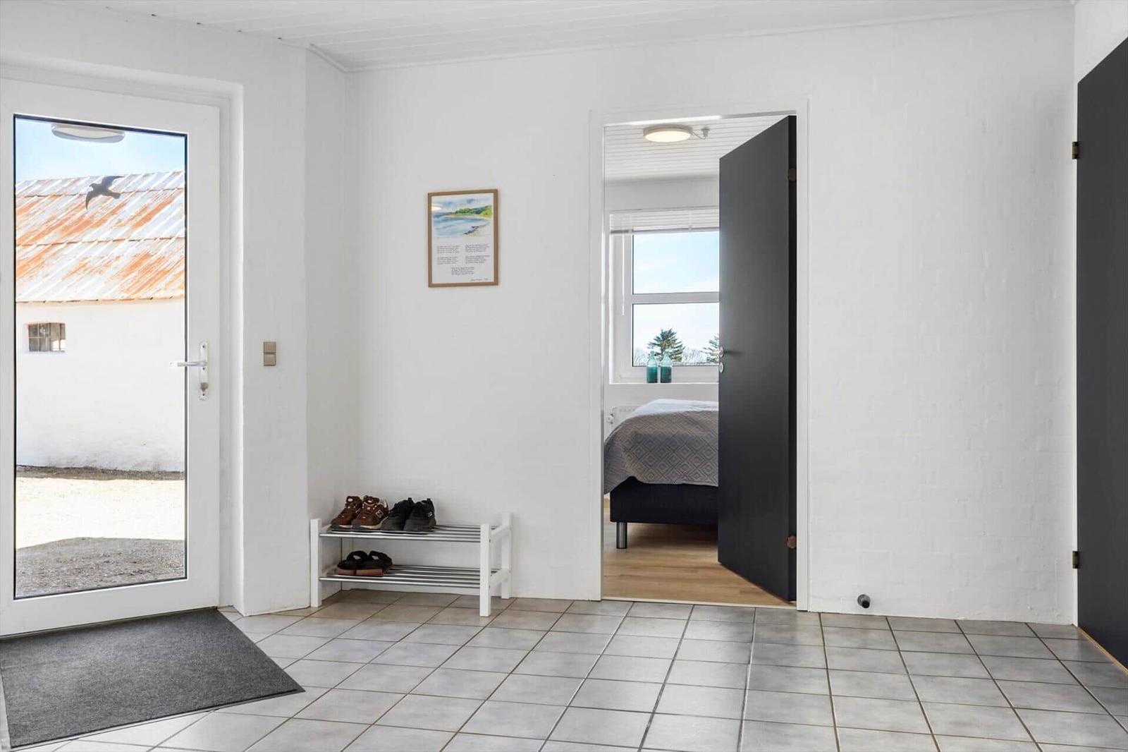 Entrance with shoe rack, door to bedroom, and window to outside.