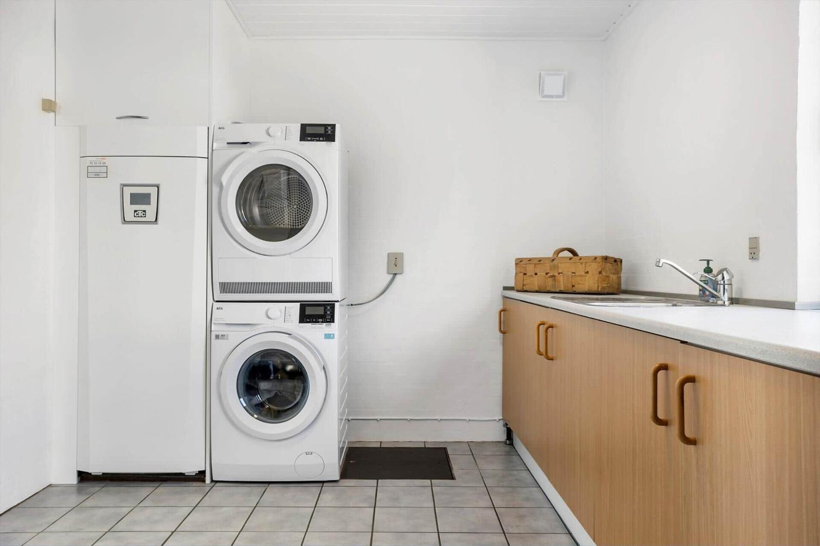 Washing machine and dryer are side by side. Kitchen counter with sink and basket.