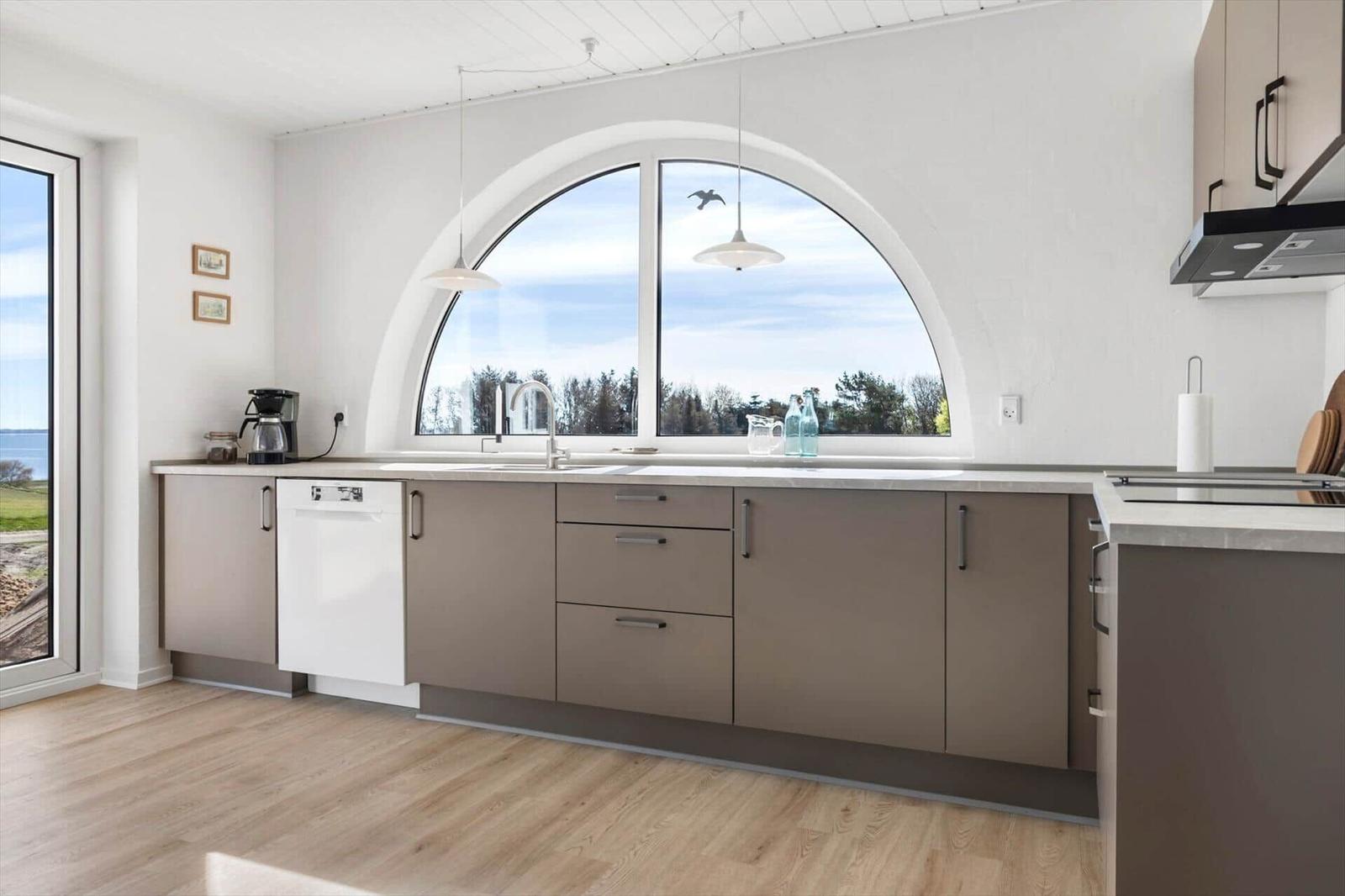 Kitchen with arched window, sink, and range hood.