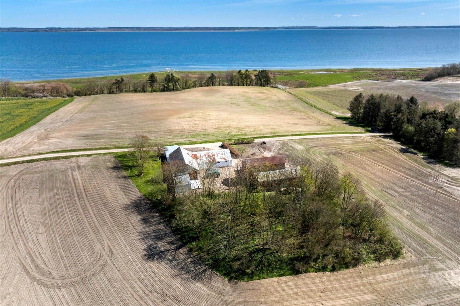 House with surrounding fields and view of a lake.