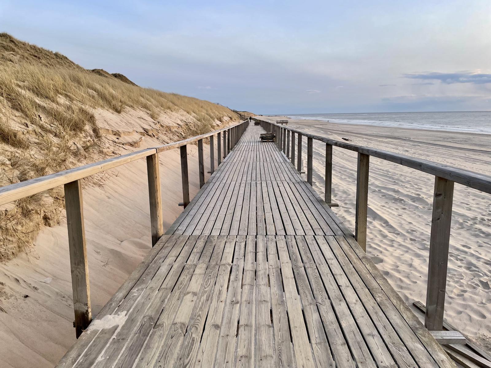 Holzweg führt von Dünen zur Strandpromenade und zum Meer.