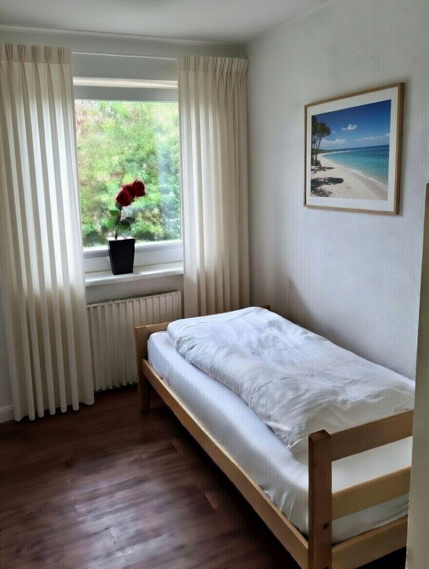 Schlafzimmer mit Bett, Fenster und Bild an der Wand.