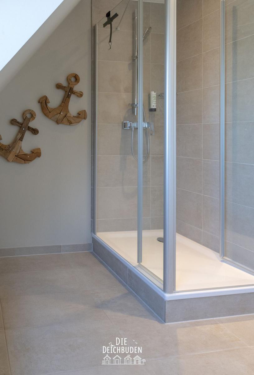 Dusche mit Glaswand und hölzernen Ankerdekoration an der Wand.