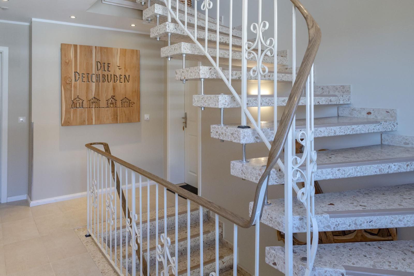 Haus mit Treppe und Holzschild mit Schriftzug. Treppenstufen aus Stein.