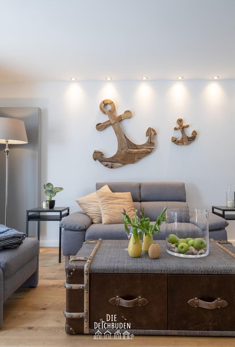Ein Wohnzimmer mit grauem Sofa, Holzwanddekoration und einem Koffer-Tisch.