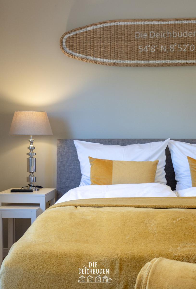 Schlafzimmer mit Bett, Nachttisch und Wanddekoration.