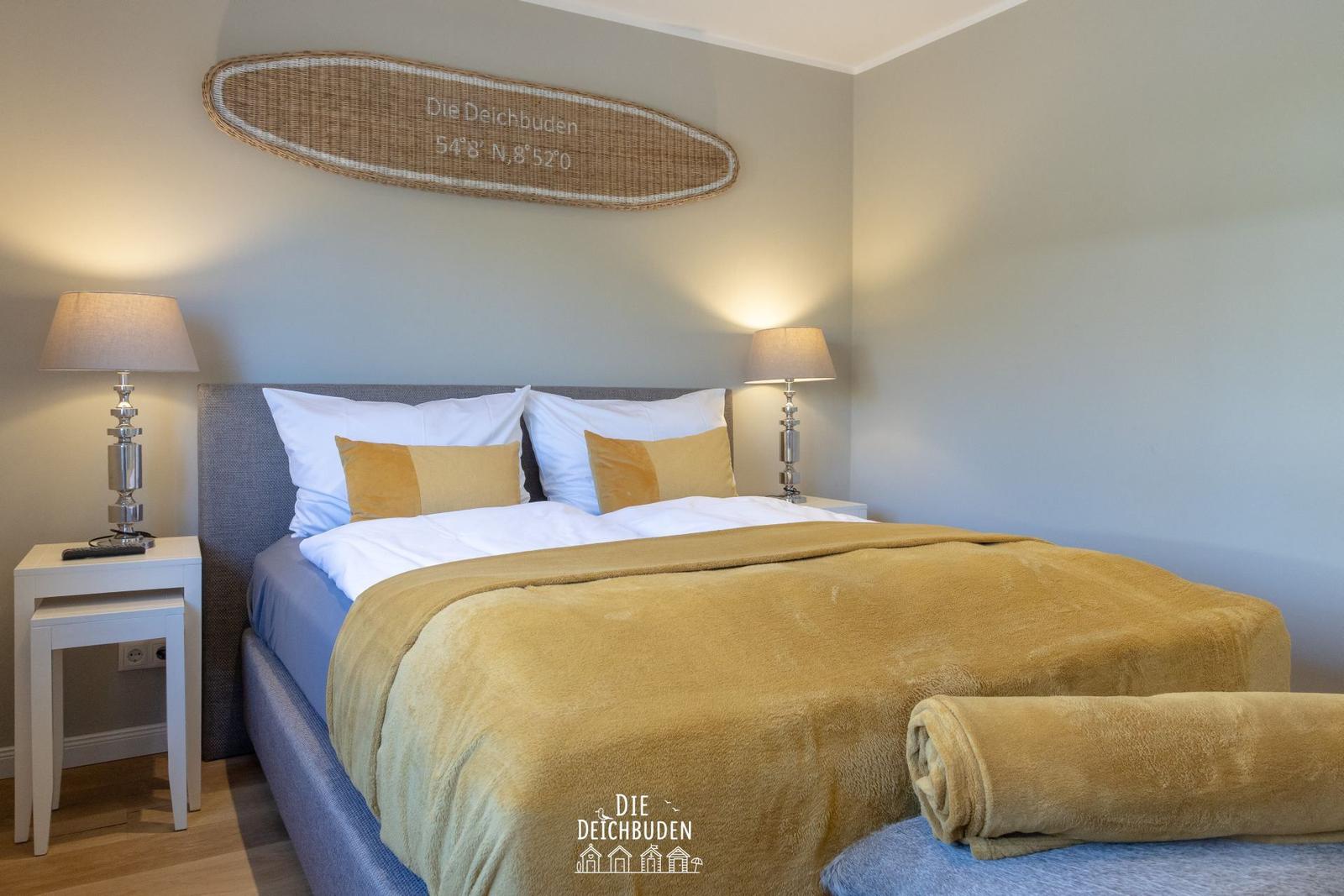 Schlafzimmer mit Bett, Nachttischen und Wanddekoration.