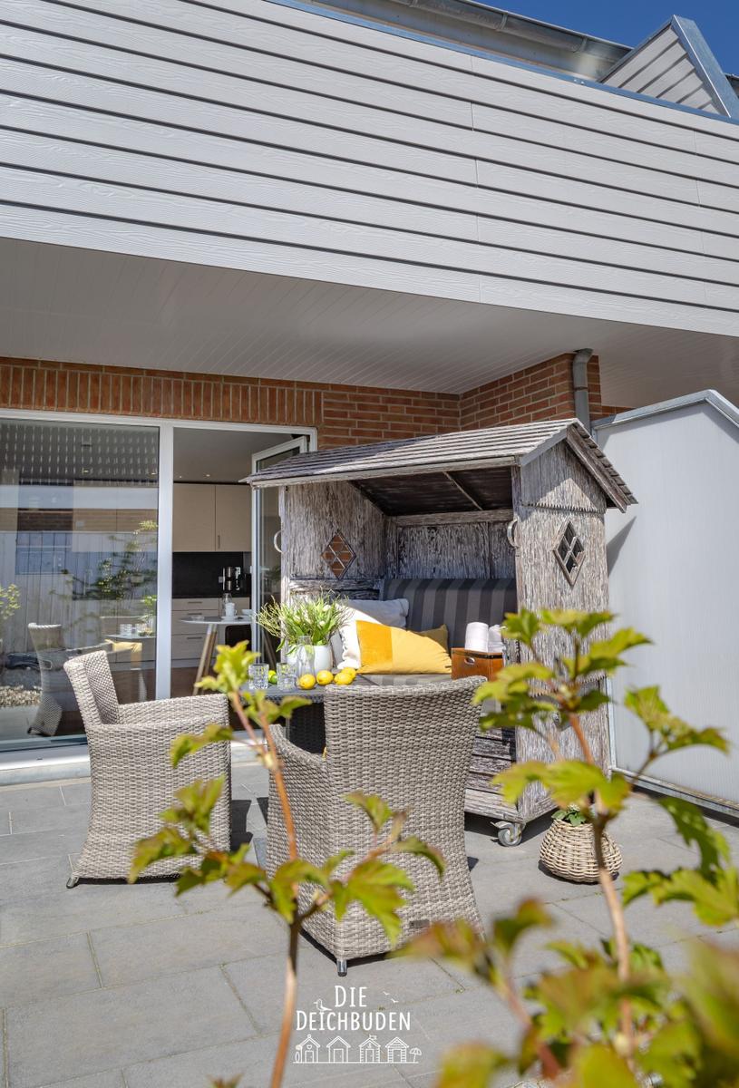 Terrasse mit Sitzgruppe, Strandkorb und Blick in die Küche.