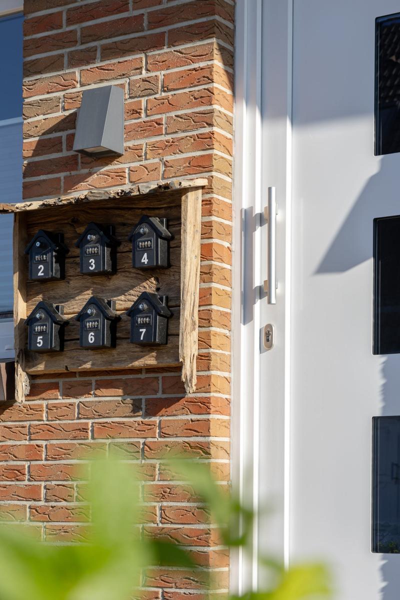 Haus mit Briefkasten für Wohnungen 2 bis 7 an einer Backsteinwand