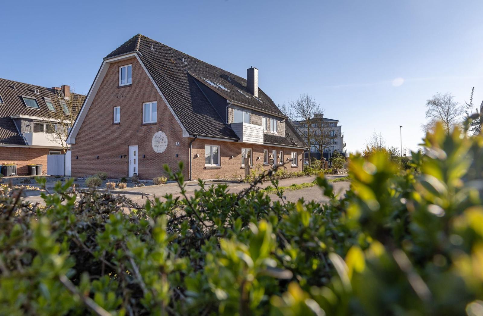 Zweistöckiges Backsteinhaus mit Dachfenstern und Vorgarten