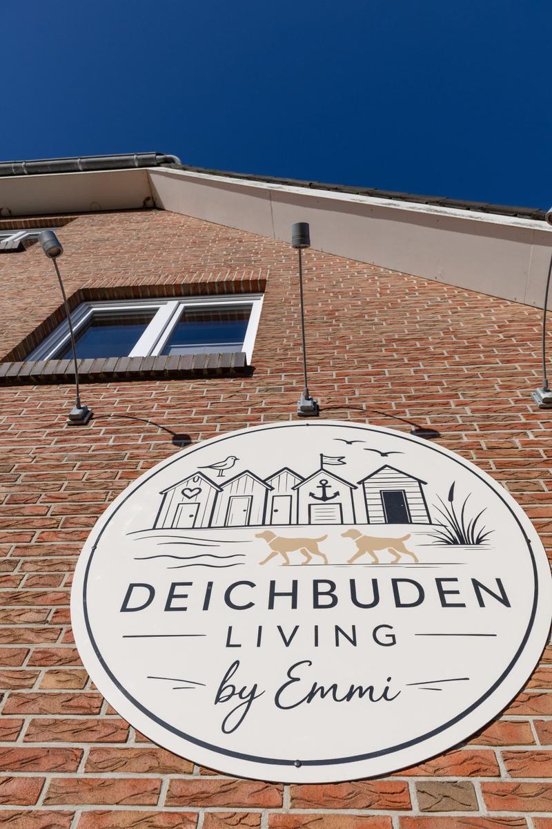 Schild an Backsteinhaus mit Strandmotiv und Schrift DEICHBU DEN LIVING