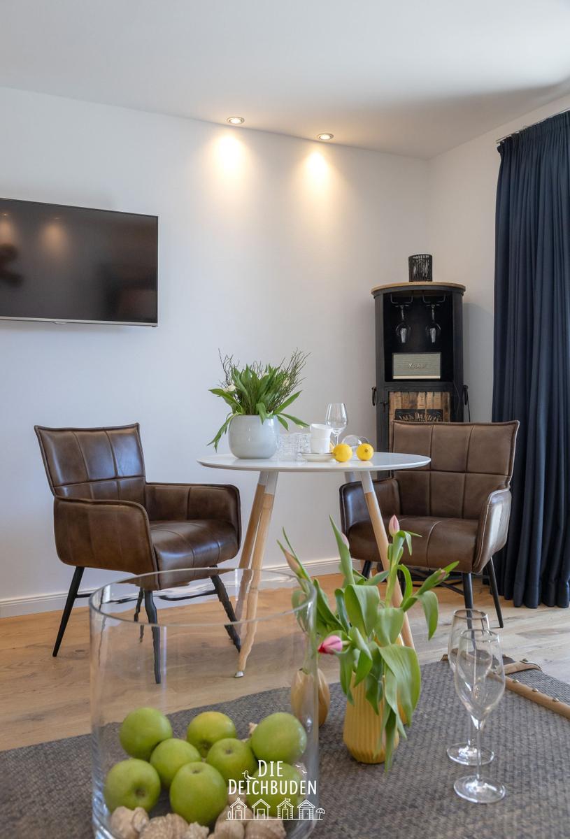 Essbereich mit zwei braunen Ledersitzen, runden Tisch und Fernseher an der Wand.
