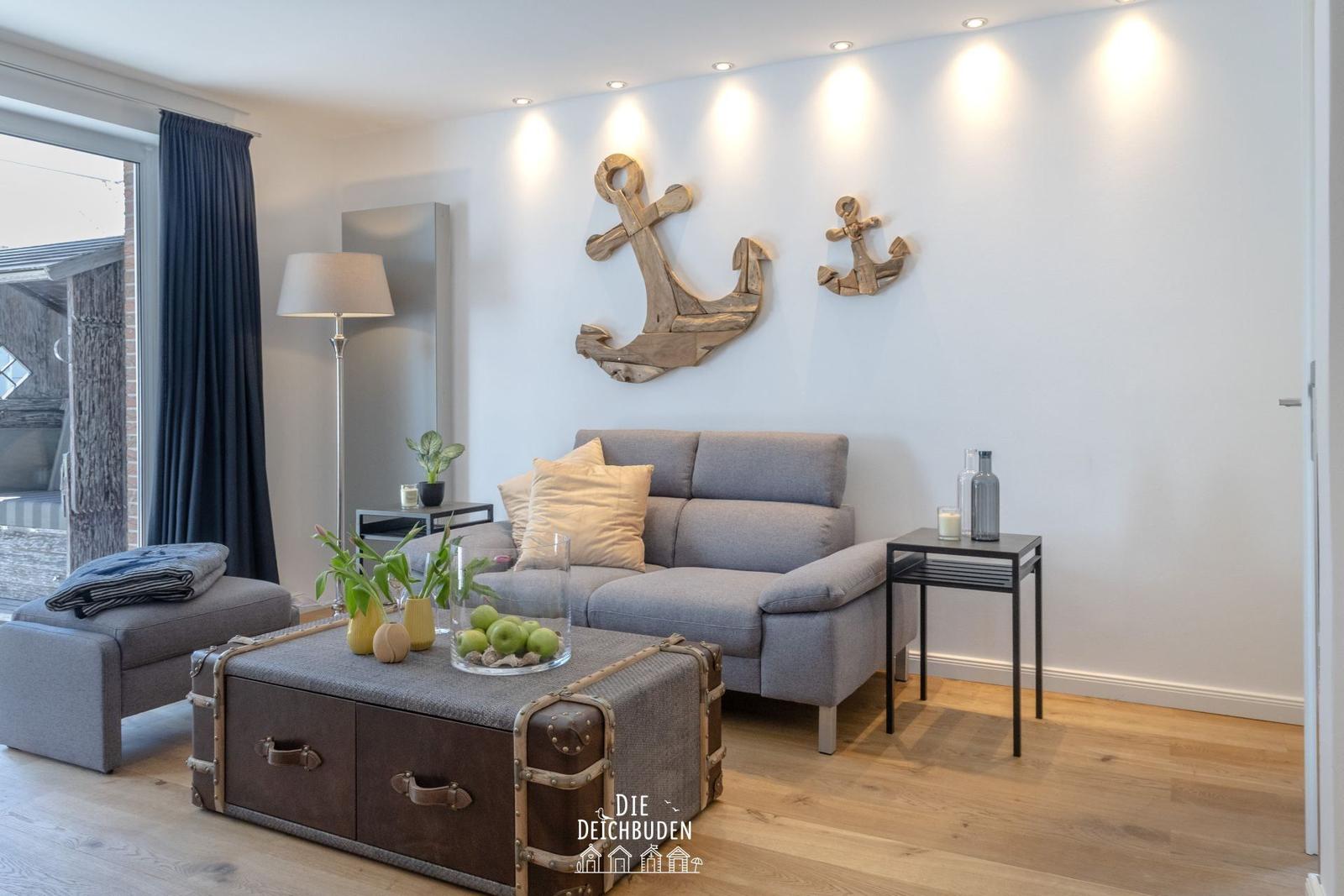 Wohnzimmer mit grauem Sofa, Holzwanddekoration und Holzfußboden.