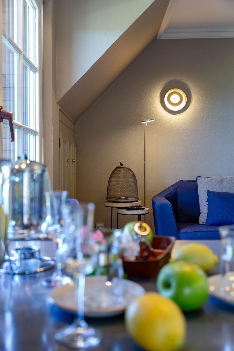 Ein Raum mit blauem Sofa, Fenster und Tisch mit Obst und Gläsern.
