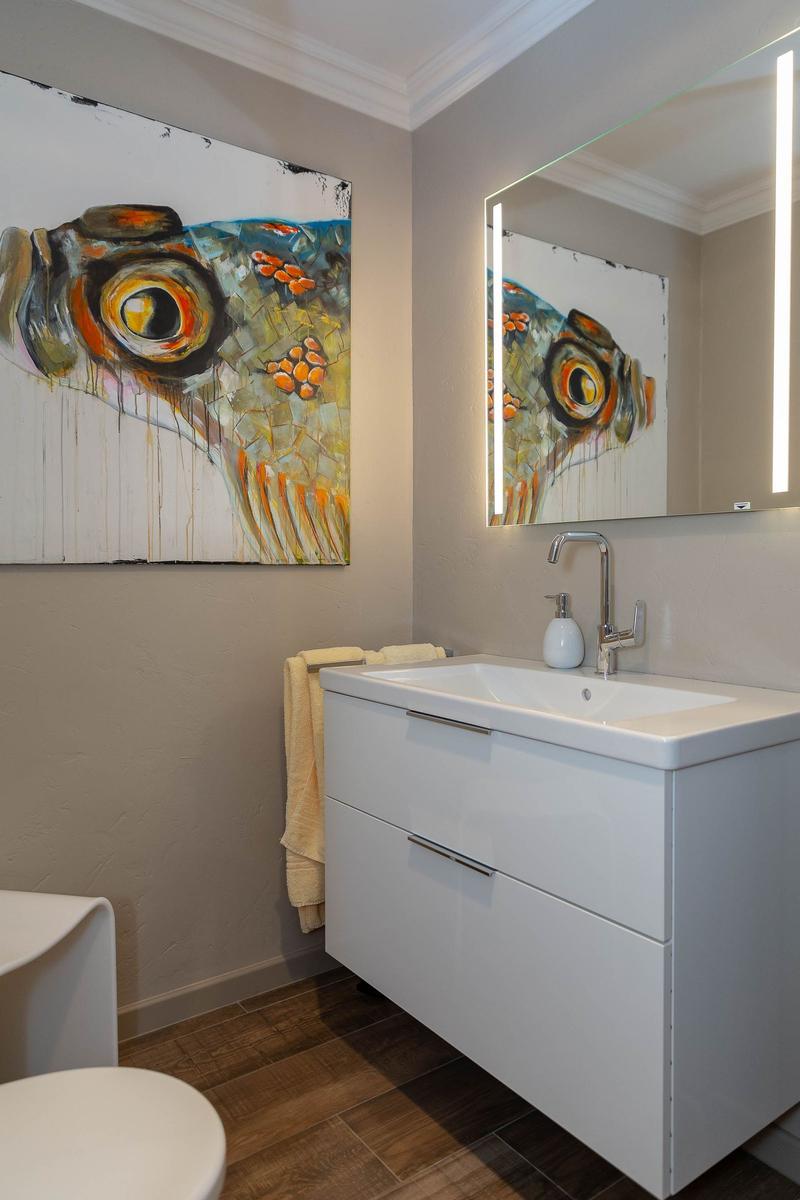 Badezimmer mit Waschbecken, Spiegel und Wandbild