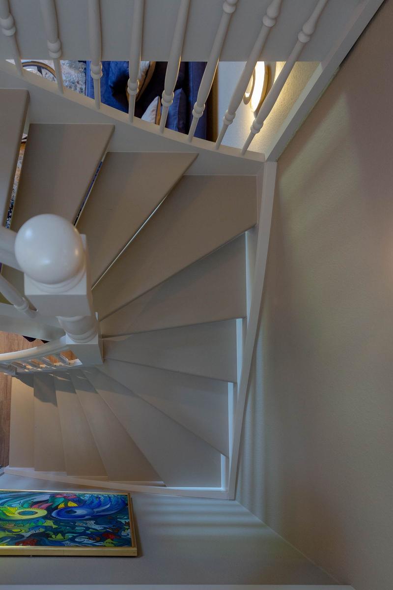 Spiralstiege mit weißer Balustrade und farbigem Bild an der Wand.