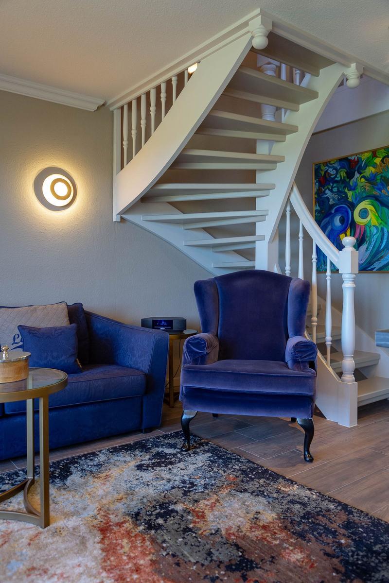 Ein Wohnzimmer mit blauer Couch, einem Sessel und einer Treppe.