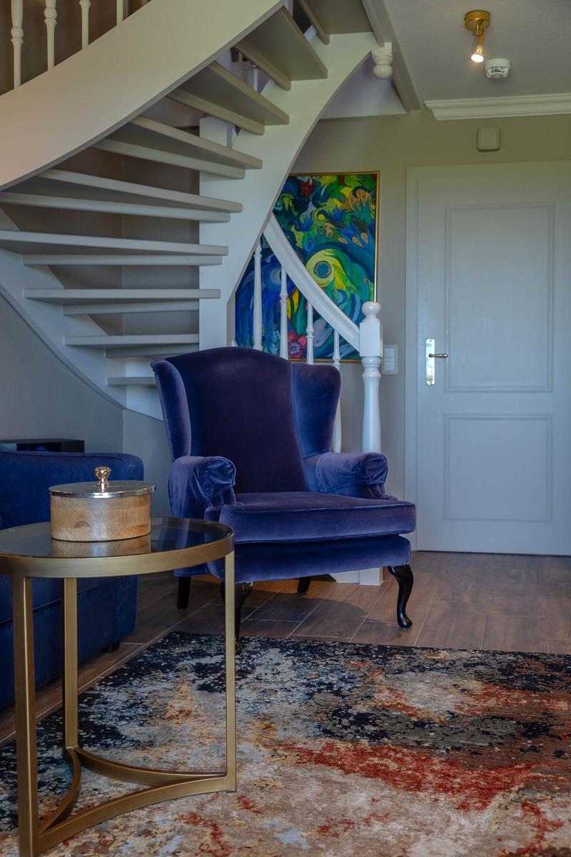 Eingangsbereich mit blauer Sitzgelegenheit, Treppe und Wandbild.