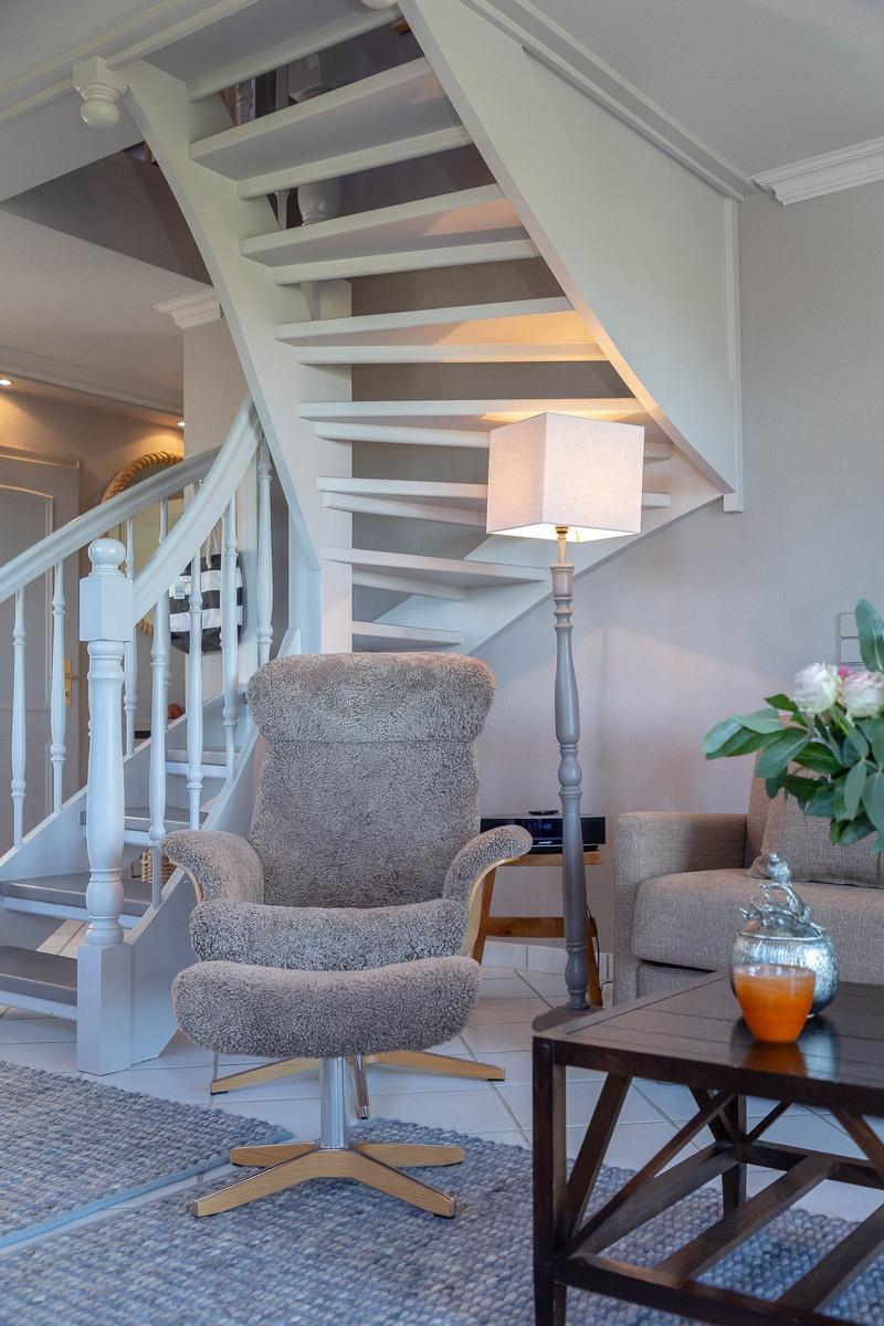 Eine Wohnzimmer-Ecke mit Sessel, Tisch und Treppe.
