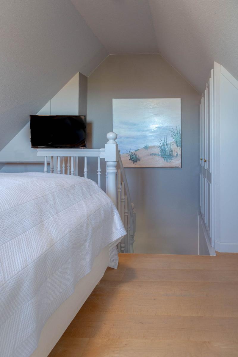 Schlafzimmer mit Dachschräge, Bett, Fernseher und Wandbild