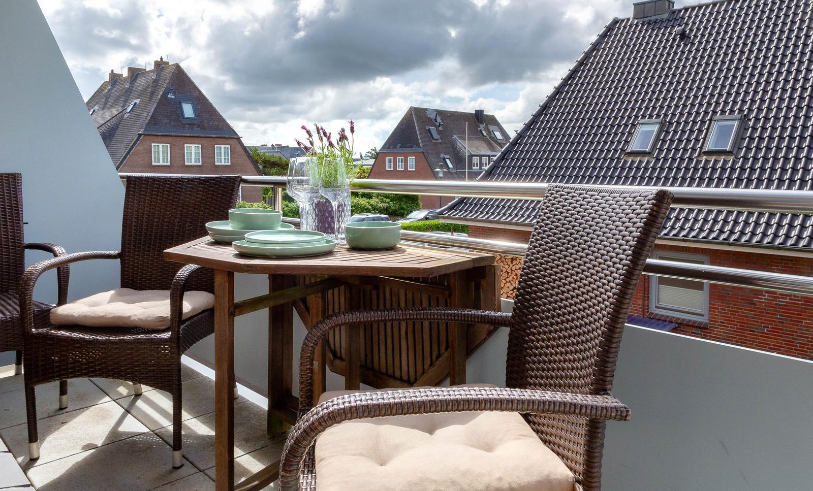 Terrasse mit Tisch, Stühlen und Blick auf Dächer.
