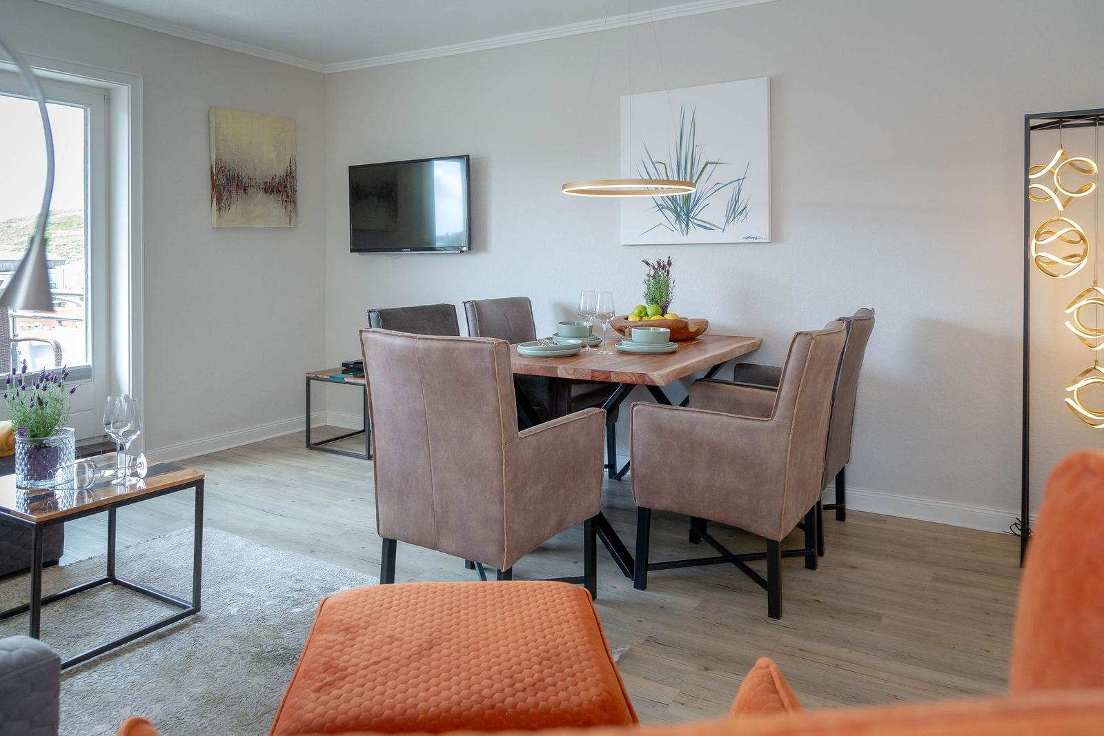 Esszimmer mit Holztisch, braunen Stühlen und Wandbildern.
