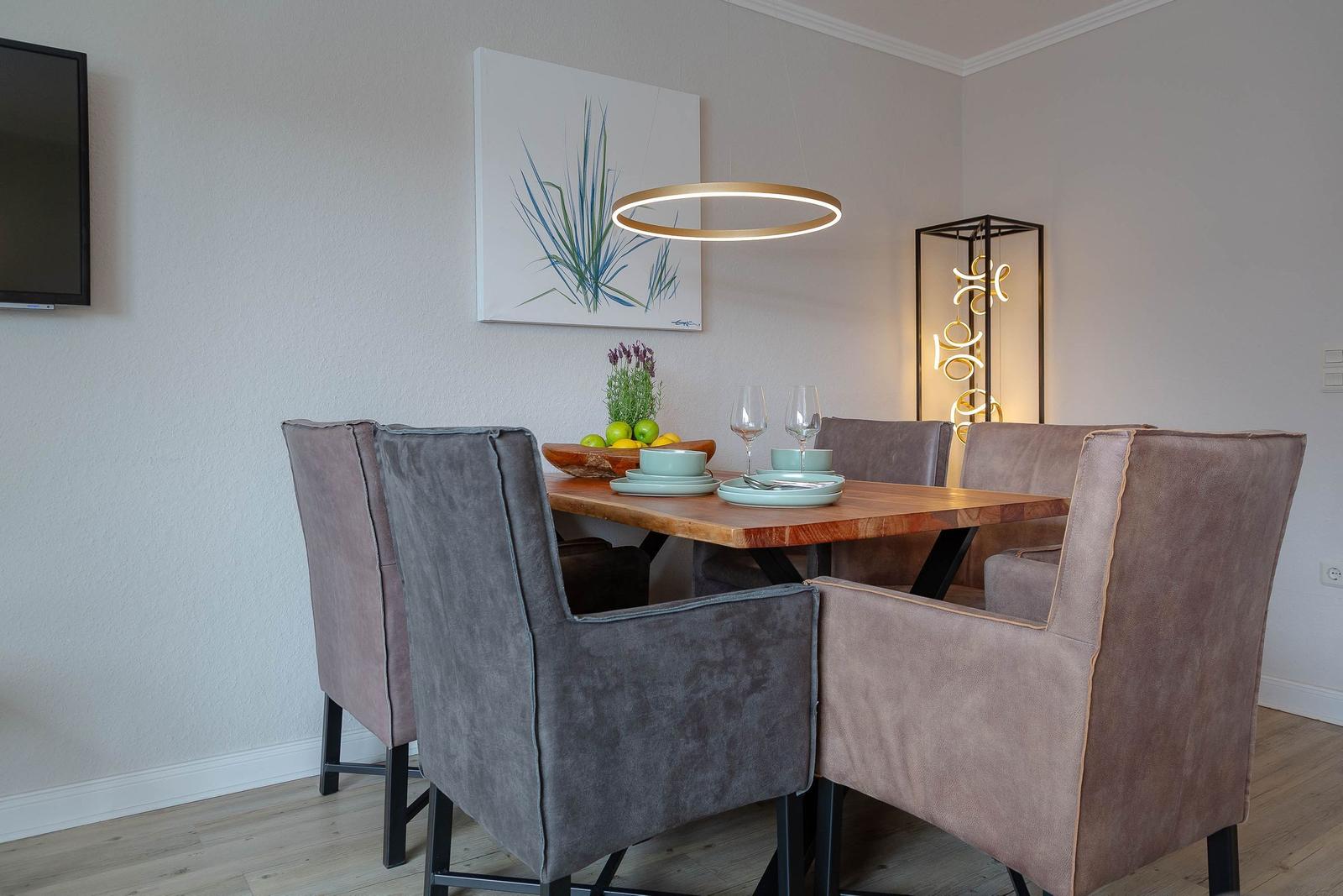 Esstisch mit sechs Stühlen, Wandbild und Deckenleuchte.