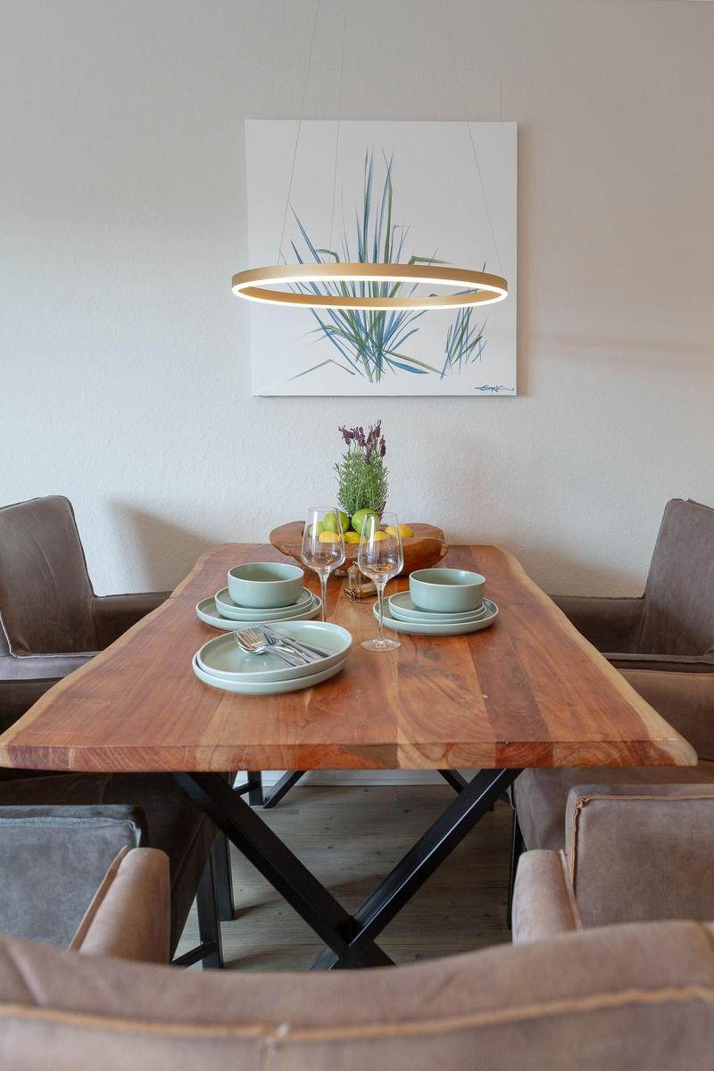 Esszimmer mit Holztisch, Stühlen und Deckenleuchte. Wandbild mit Pflanzenmotiv.