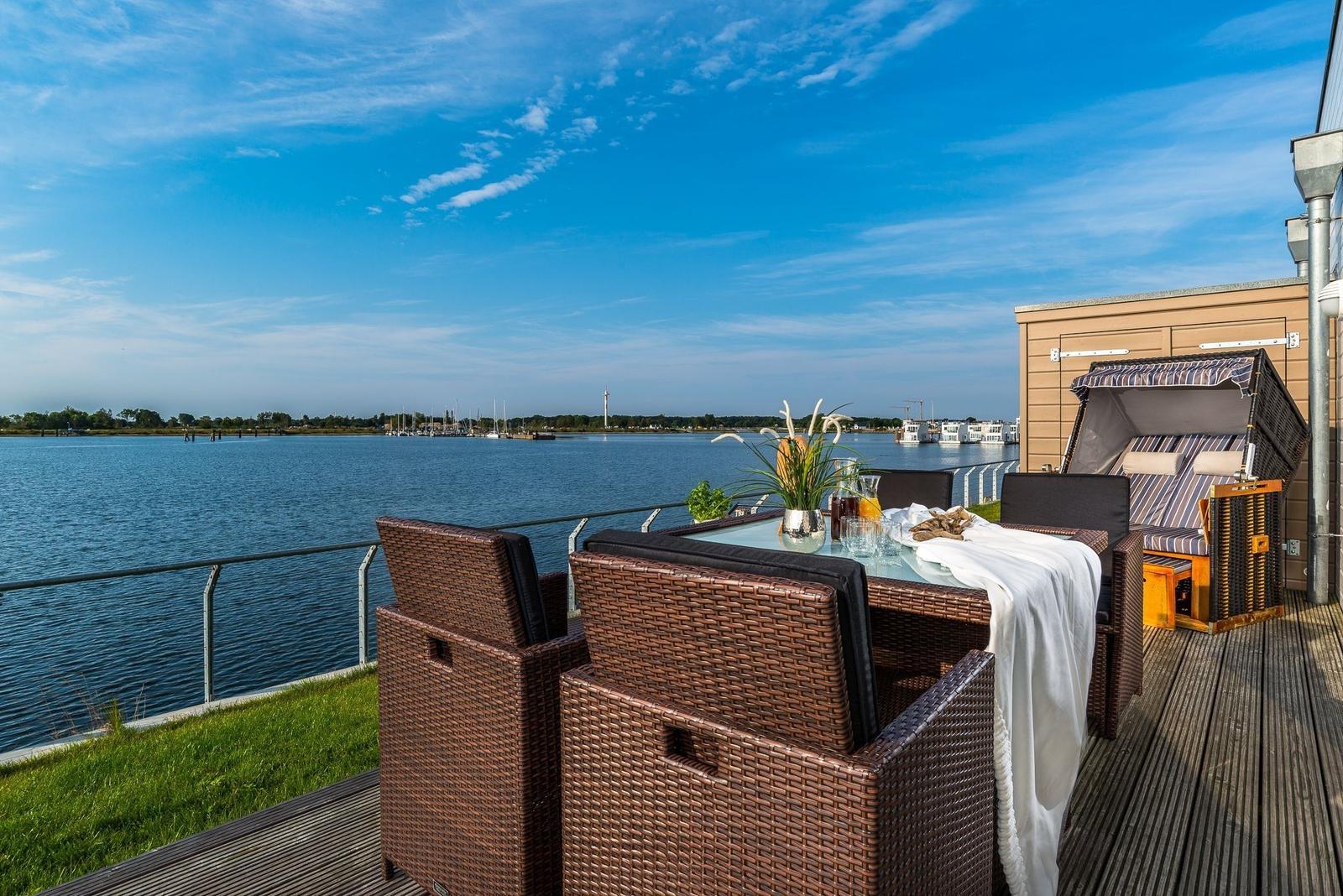 Terrasse mit Sitzgelegenheiten und Blick auf Wasser und Hafen.