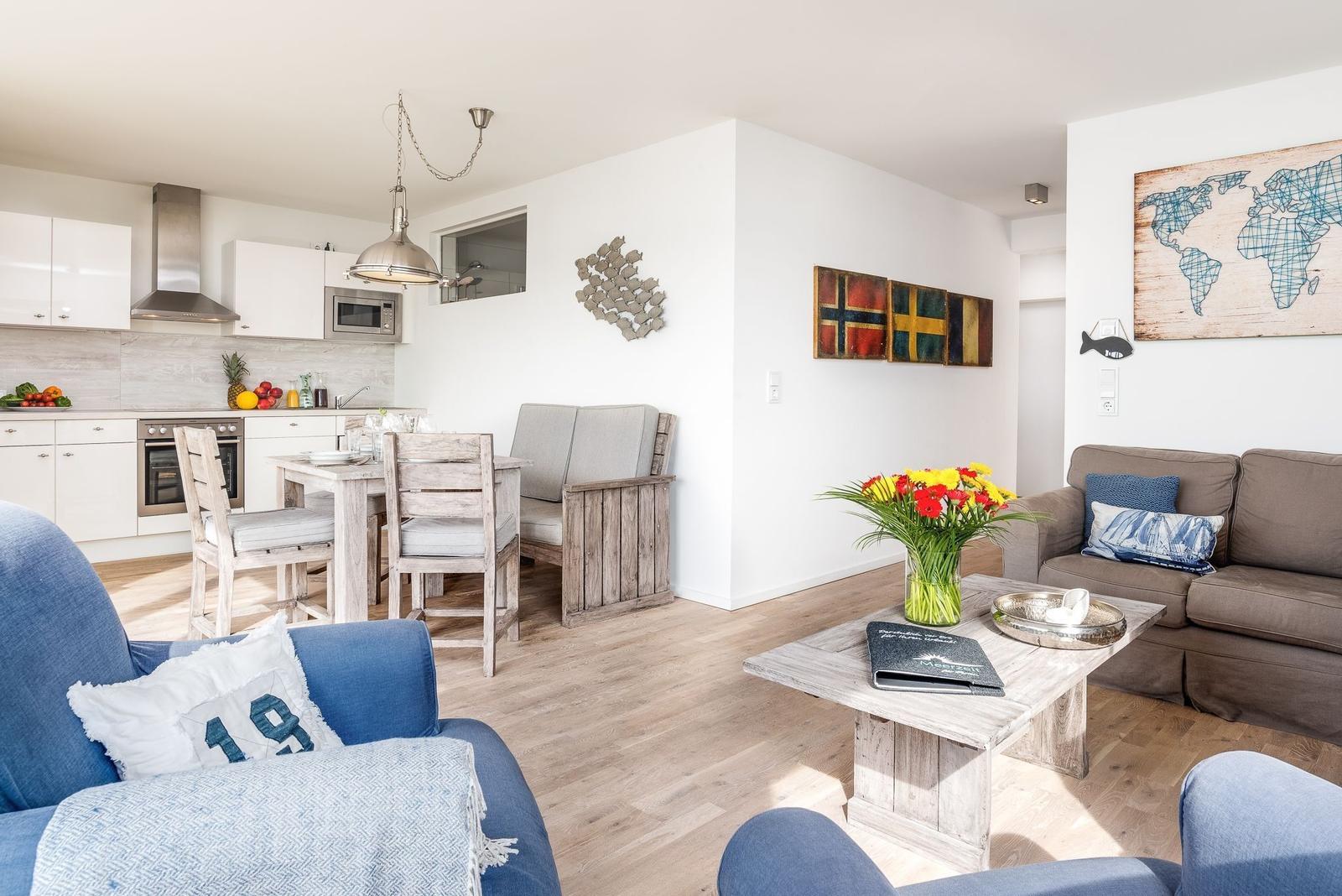 Wohn- und Küchenbereich mit Holzboden, Sofa, Esstisch und Küchengeräten.