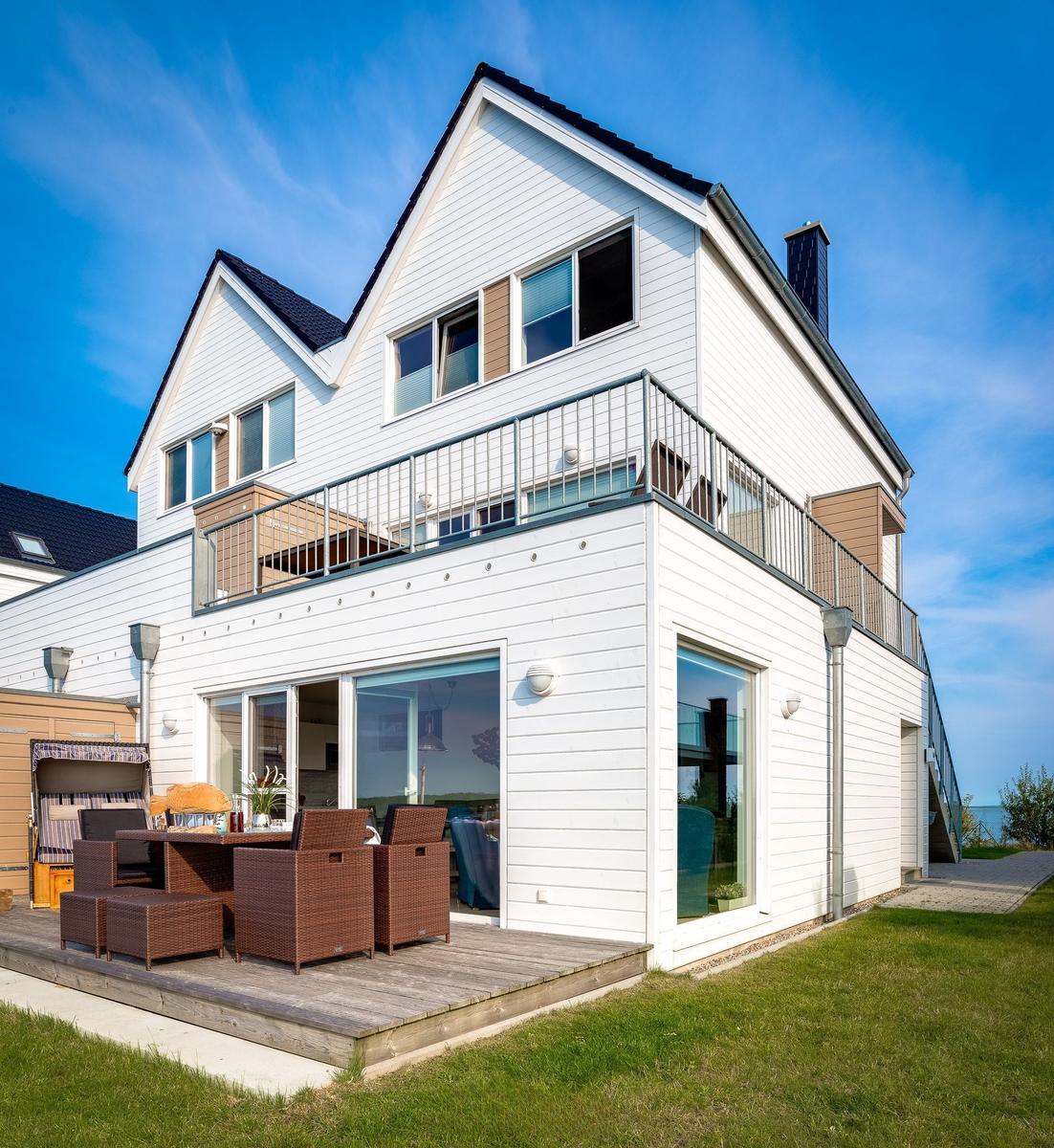 Modernes Haus mit Balkon und Terrasse mit Gartenmöbeln. Blick auf den Himmel.