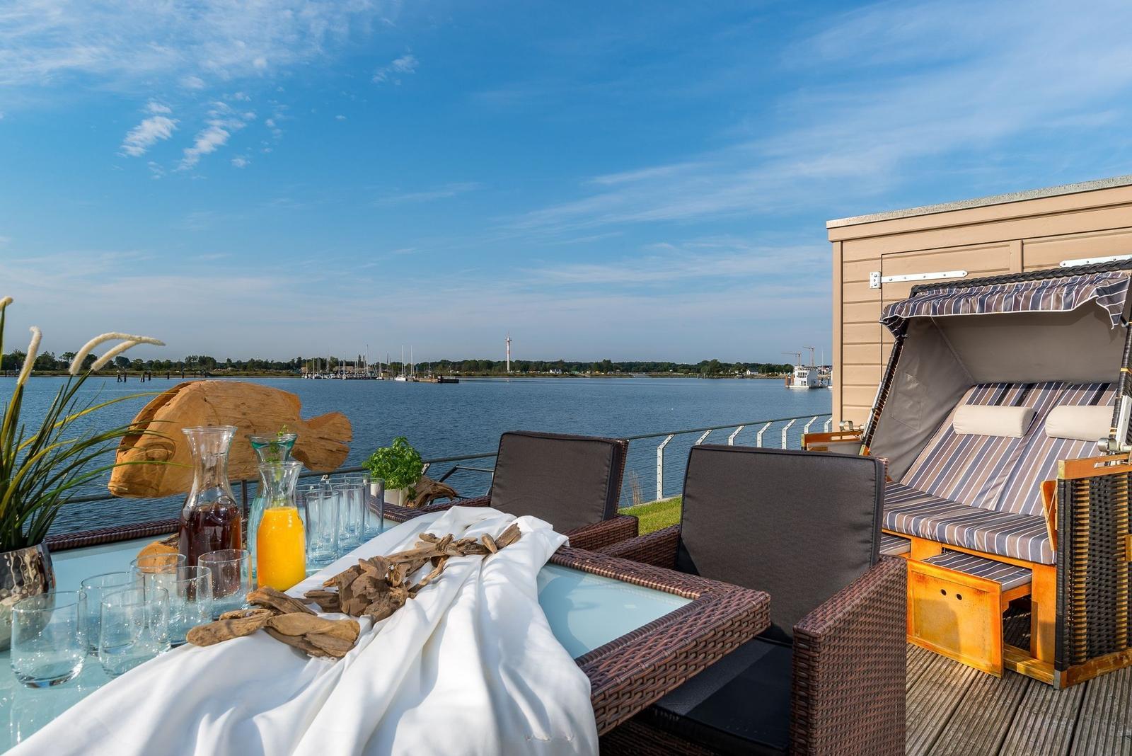 Terrasse mit Tisch, Stühlen und Liege am Wasser