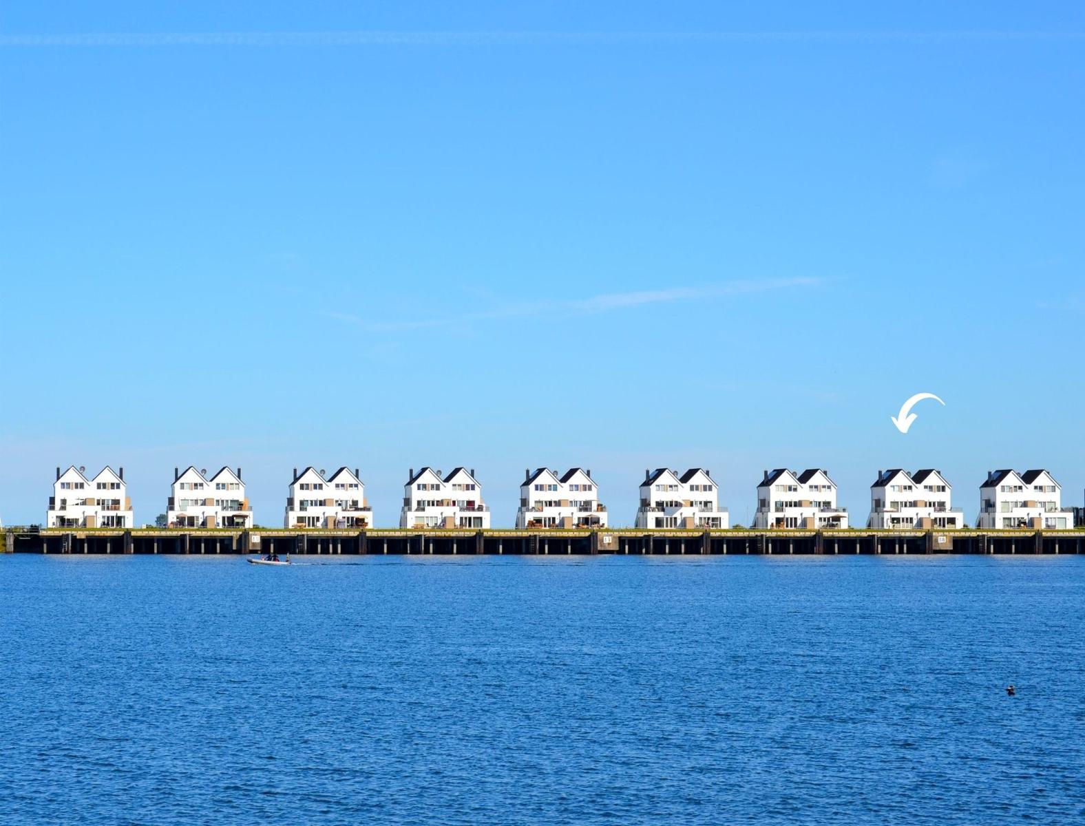 Row of white houses along a waterfront under a blue sky.