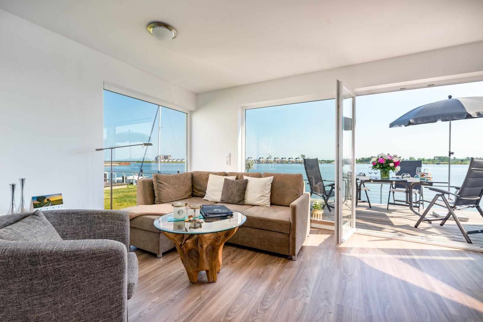 Living room with water view, sofa, table, and terrace with seating.