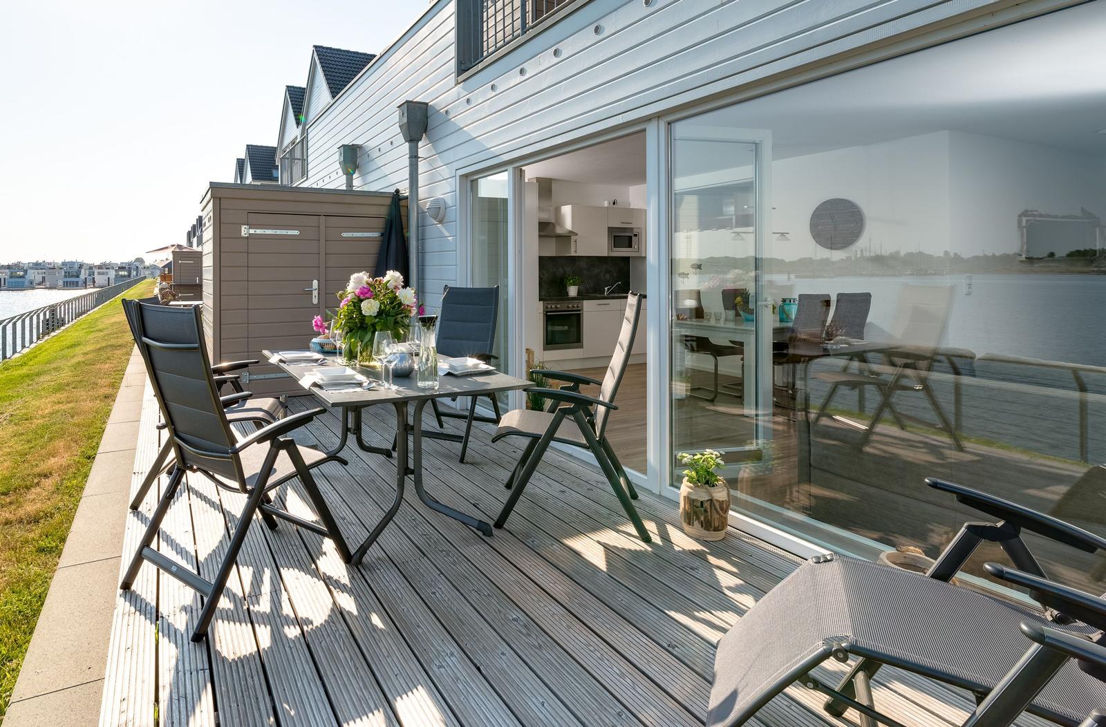 Deck with table and chairs, view of water and kitchen area.