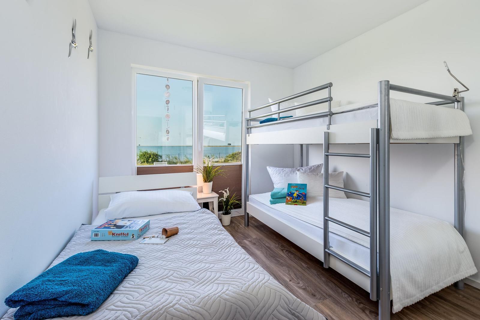 Room with bunk bed and single bed, window with sea view.