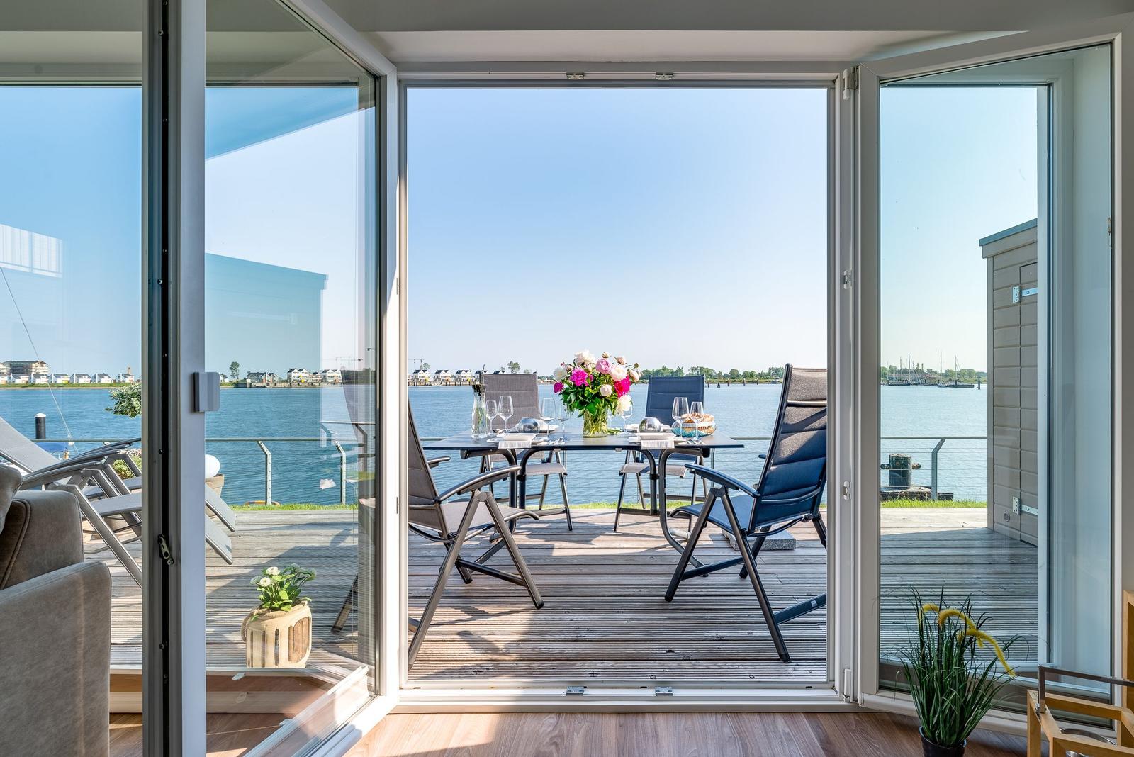 Deck with table, chairs, and flowers by waterfront