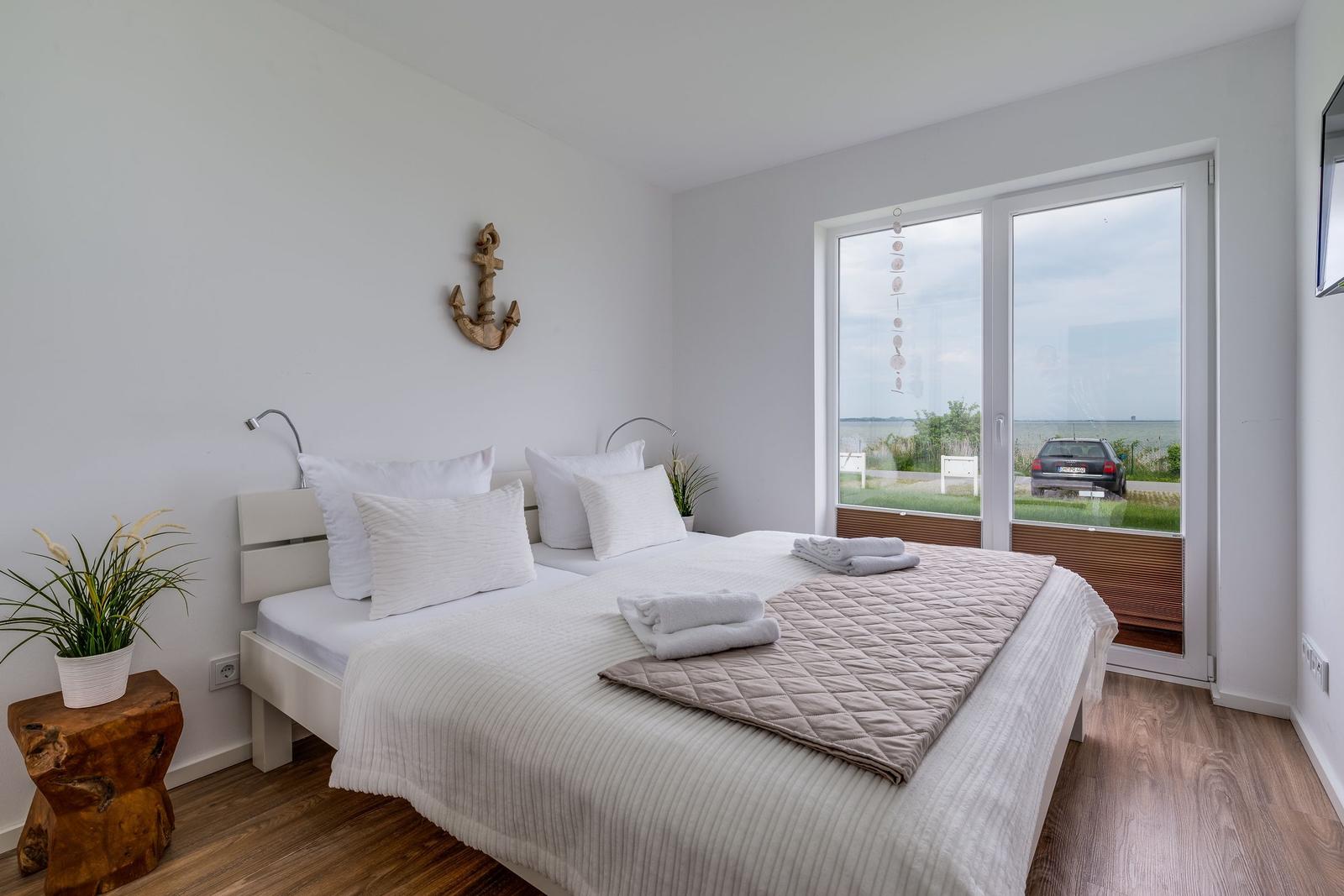 Bedroom with bed, window view, and wooden floor.