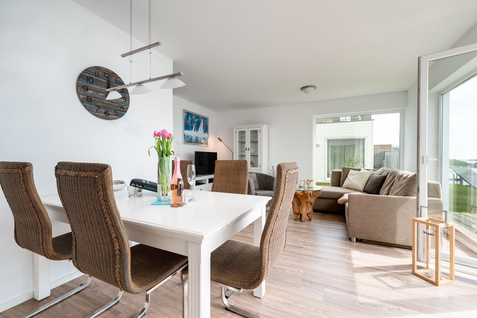 Dining area with table and chairs, living area with sofa and windows