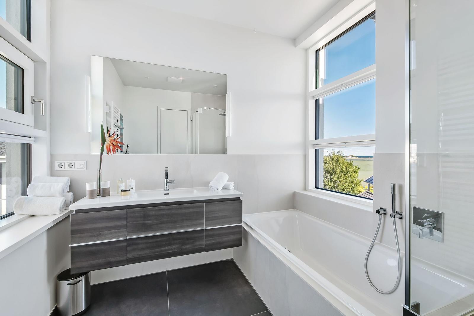 Badezimmer mit Badewanne, Dusche und Waschbecken mit Spiegel.