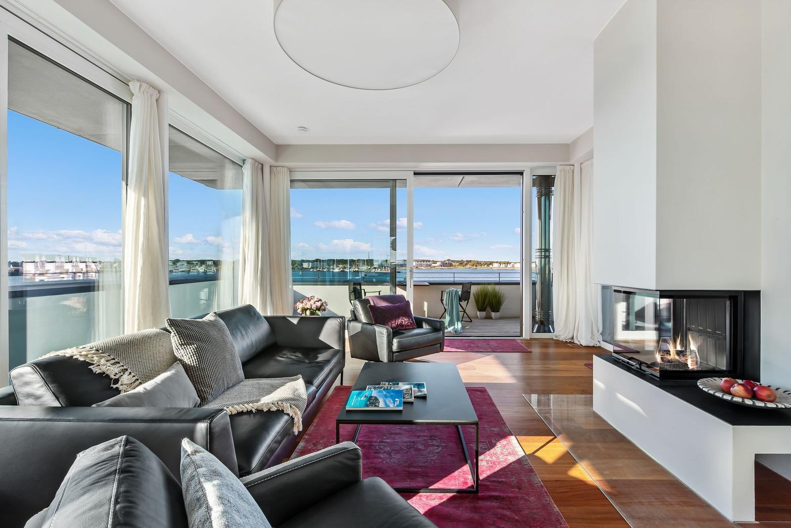 Wohnzimmer mit Sofa, Kamin und Blick auf Hafen