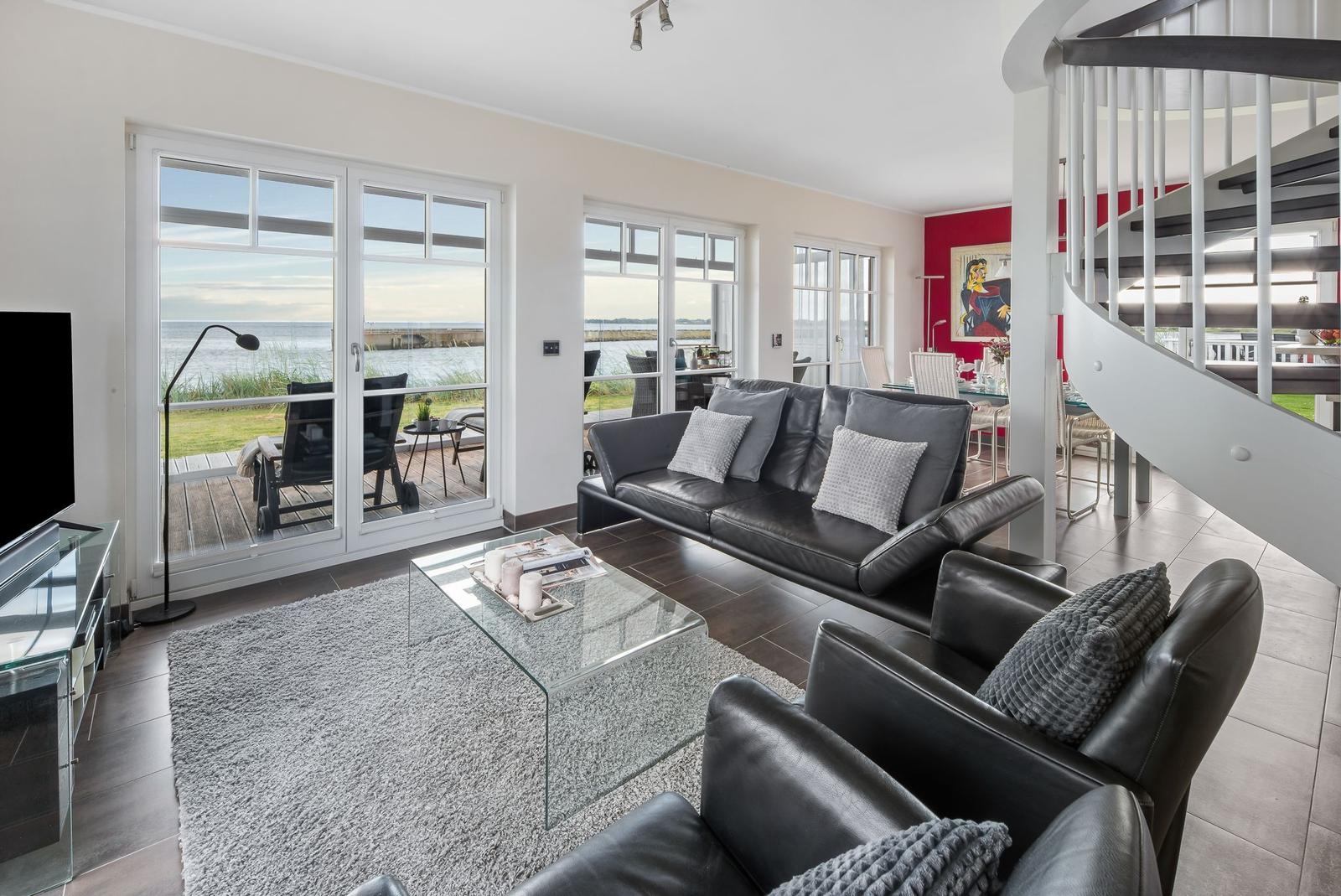 Wohnzimmer mit Sofa, Sessel und Blick aufs Meer.