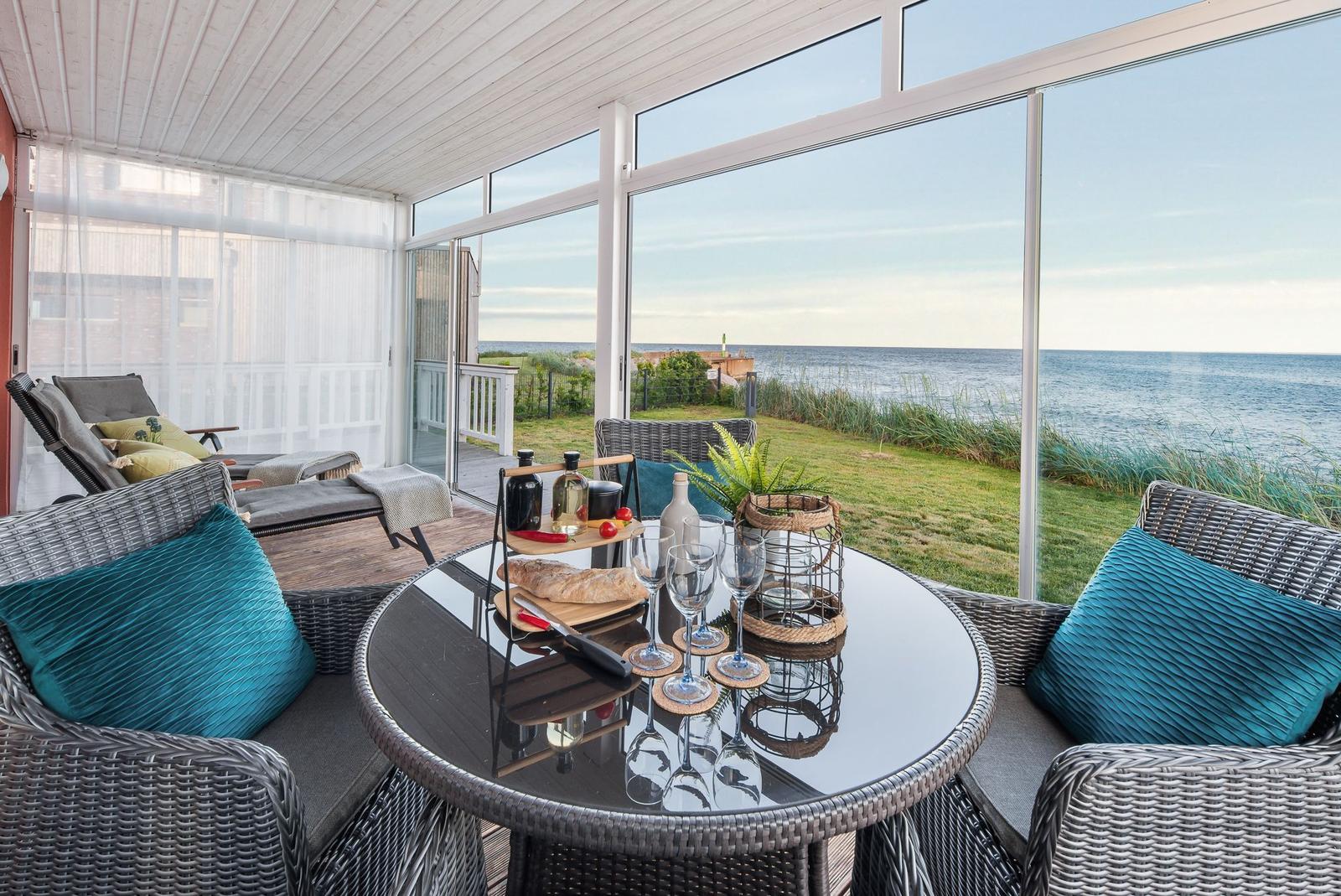 Terrasse mit Sitzgruppe und Tisch. Blick auf das Meer und Grasland.