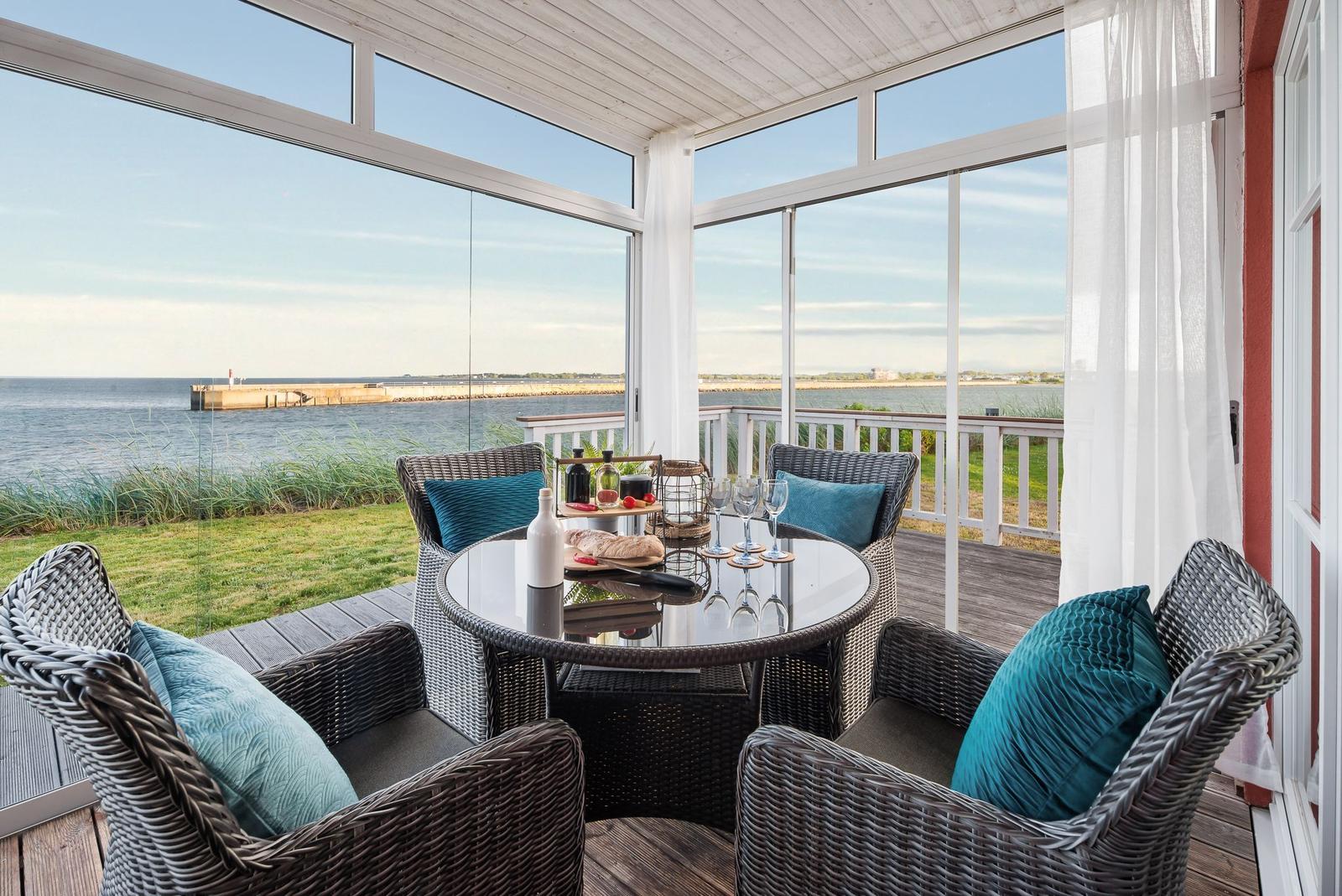 Terrasse mit Sitzgruppe und Meerblick durch Glaswände