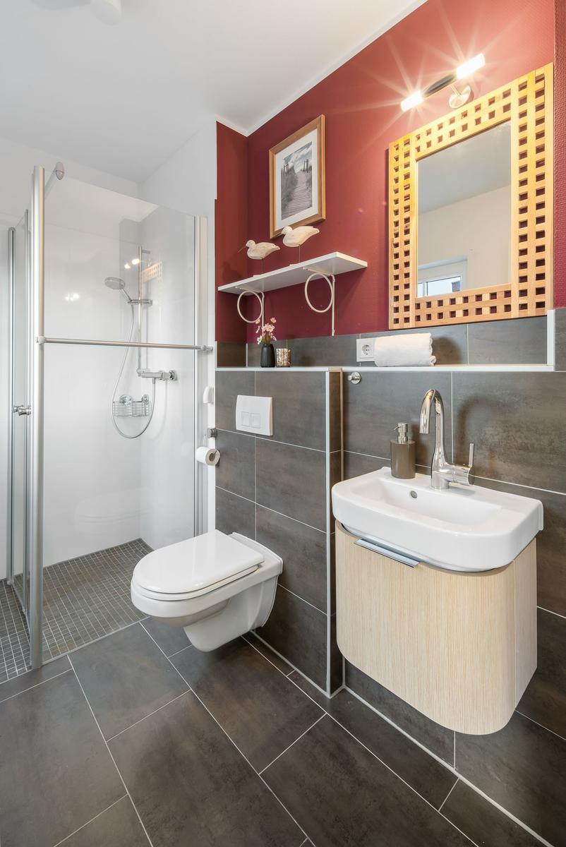 Badezimmer mit Dusche, Toilette und Waschbecken mit Spiegel.